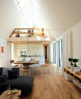 Living room with dining area, high ceiling and integrated gallery with skylights