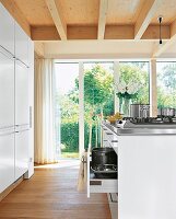 Helle Küche mit raumhohen Fenstern, Holzdecke und Holzfussboden
