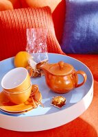 Orange teapot with cups in serving dish