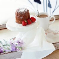 Bundt cake with icing sugar and strawberries on cake stand