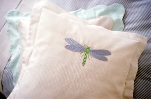 Close-up of blue and white cushion with embroidery of dragonfly