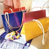 Vier Handtaschen in verschiedenen Farben.