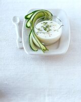 Cream cheese horseradish in glass bowl with sliced cucumber on plate