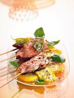 Pork skewer kept on zucchini with basil leaves on glass plate