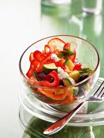 Bowl of salad with courgette, red pepper and cheese kept on glass plate