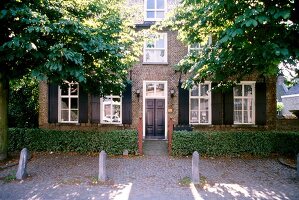 Altes Backsteinhaus in Nuenen, grüne Fensterläden, Hecke, Bäume