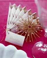 Close-up of place cards from wrapping paper in accordion shape on pink background