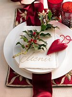 Branch of Ilex, heart shaped pendant and menu card lying on white plate