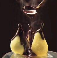 Drei Birnen werden mit heißer Schokoladensauce begossen