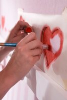 Close-up of kids room wall being painted with red heart