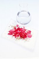 Jar of water and dried petals on white background
