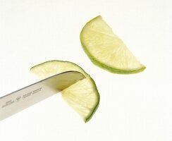 Lime slices being cut in quarters with knife