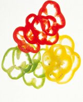 Red, yellow and green pepper slices on white background