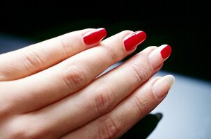 Close-up of woman applying red base coat her fingernails, step 2