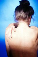 Rear view of woman massaging her shoulders