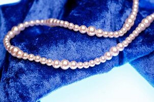 Perlenkette auf einem blauen Tuch. 