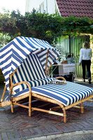 Rattanliegestuhl mit Faltdach auf Terrasse im Garten, blau-weiß