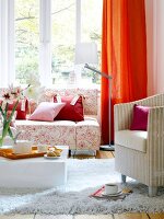 Living room with floral designed sofa, wicker chair, table and white fur carpet