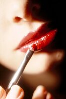Close-up of woman applying red lipstick on lips