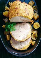 Roast pork with mustard crust and onions in baking dish, overhead view
