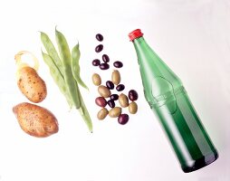 Peas, olives, bottle of water and two potatoes on white background