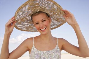 Jennifer Fröhliche junge Frau am Strand mit einem großen Strohhut