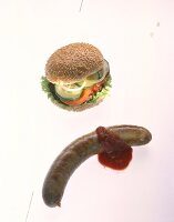 Hamburger with cucumber, tomato, onions and lettuce and currywurst