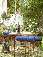 Eisenstühle um einen Tisch in einem grünen Garten, Wein und Gläser