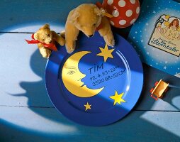 Soft toys on blue plate with moon, stars, names, height and weight