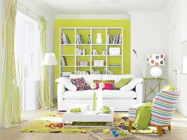 Wohnzimmer mit weißem Sofa, grüner Wand und bunten Accessoirs