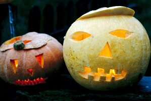 Close-up of two carved pumpkins with lit candles