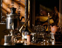 Three types of teapots, teapot warmer, sugar bowl, tea liqueur, mugs and burning candle