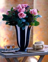 Pink roses in black and white striped flower vase on table