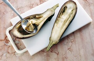 Eggplant being scooped with spoon on chopping board