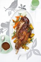 Roasted leg of lamb with potatoes and carrots on serving dish