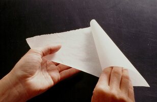 Triangular baking paper being rolled into a bag, step 2