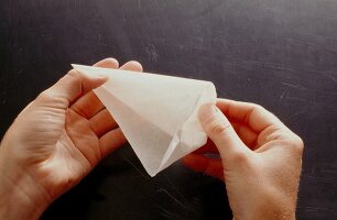 Edges of triangular baking paper being folded, step 4