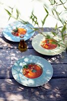 Three plates of melon gazpacho with toasted pine nuts on table