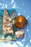 Melon and apricot jam with vanilla in glass jar nest to a baguette