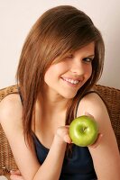 Portrait of woman with long hair holding green apple, smiling