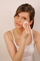 Side view of gray eyed Magdalena woman with brown hair cleaning her face with pad