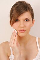 Portrait of gray eyed Magdalena woman with brown hair cleaning her face with pad