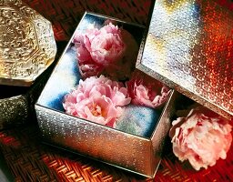 Close-up of three peonies bloom in silver box