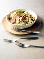 Bowl of chicken and chanterelle risotto with fork on plate