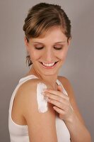 Charlotte woman with blonde hair applying lotion on her arm looking down, smiling