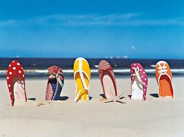 bunte Schuhe im Sand aufgereiht 