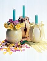 Egg shaped candlesticks with flowers, blue candles and scattered flower petals