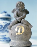 Close-up of stone statue with angel figurine and initials in gold