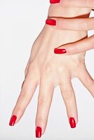 Close-up of woman with hands clasped wearing red nail paint