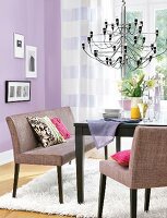Dining table with bench seat and chandelier against purple wall
